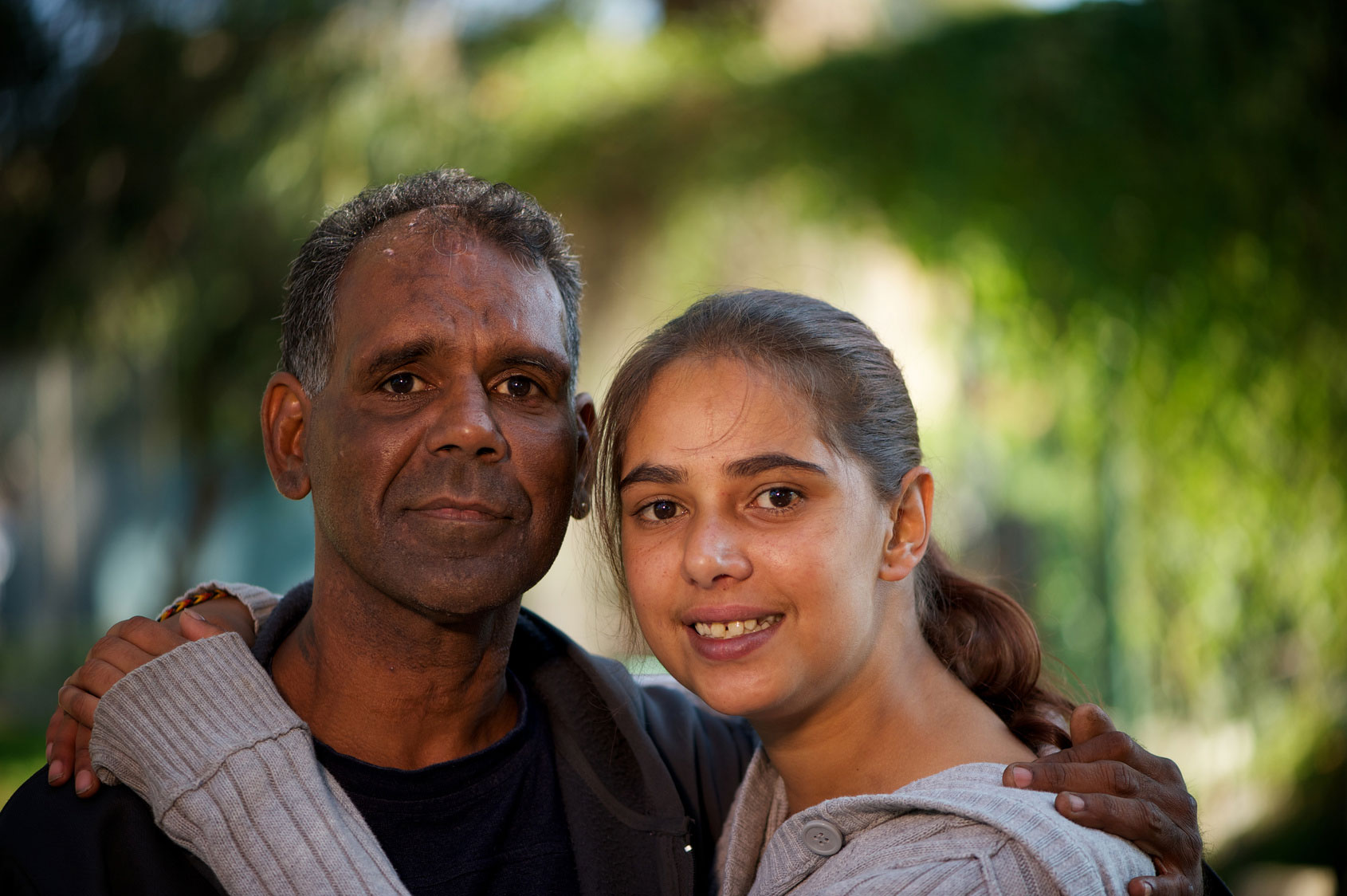 Father and daughter embracing while looking at camera and smiling