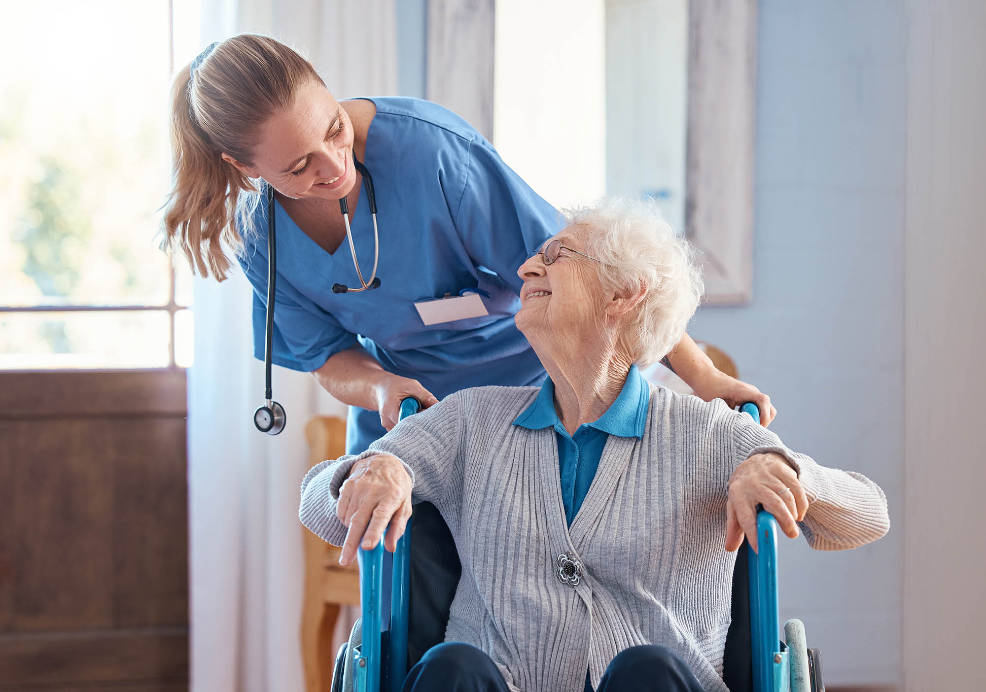 Female nurse pushing elderly woman in wheelchair