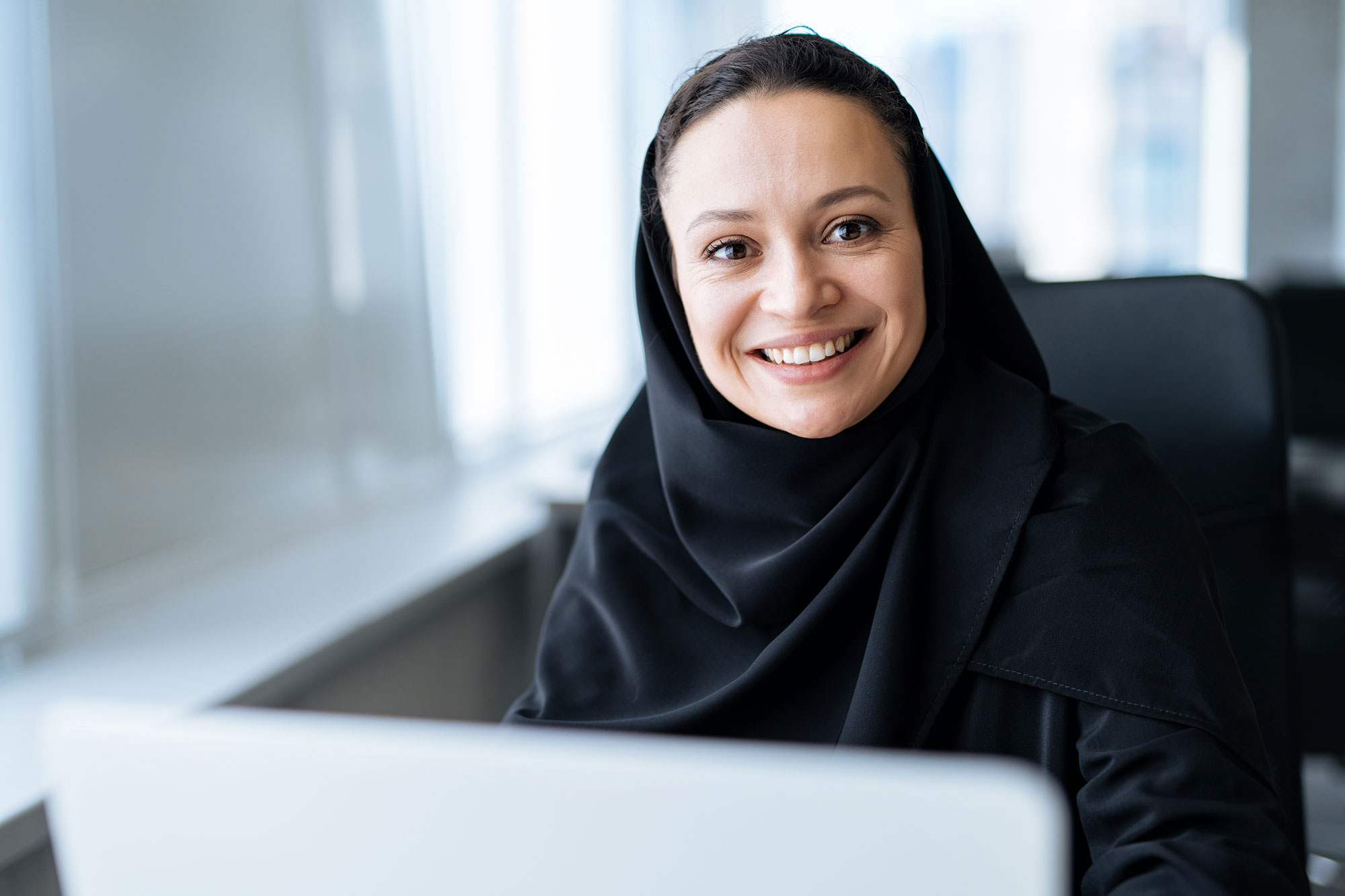 Women on a computer smiling and looking at the camera