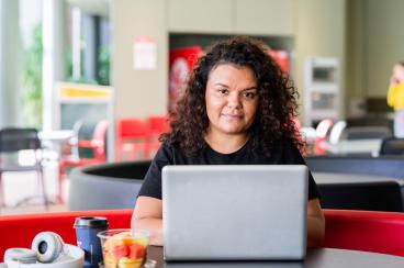 Woman behind a laptop computer looking att he camera