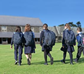 School children walking to class through a grassy field