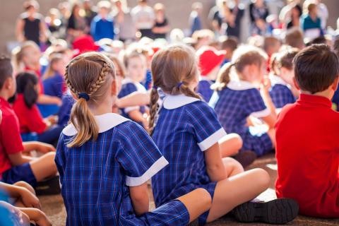 School children sitting down with their backs facing the camera