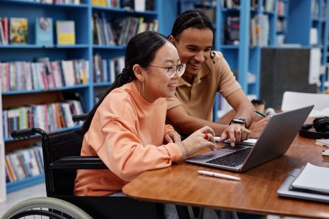 Teacher helping young student in a library